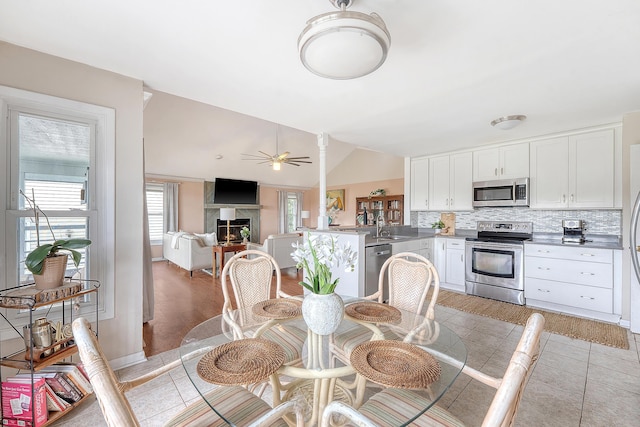 4636 Ashley View Ln, North Charleston, SC 29405 - dining room with a lit fireplace, ceiling fan, lofted ceiling, and light tile patterned floors