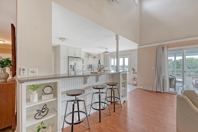 4636 Ashley View Ln, North Charleston, SC 29405 - kitchen featuring stainless steel refrigerator with ice dispenser, a kitchen breakfast bar, light wood finished floors, white cabinets, and ornate columns