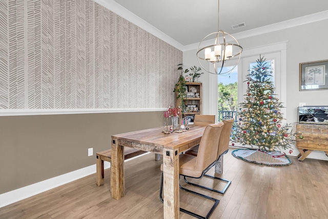 dining room with light wood-type flooring, ornamental molding, and a notable chandelier