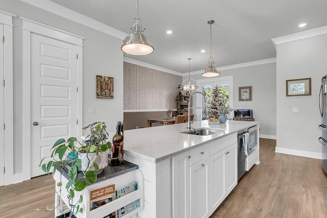 kitchen with white cabinetry, sink, hanging light fixtures, light hardwood / wood-style flooring, and a center island with sink