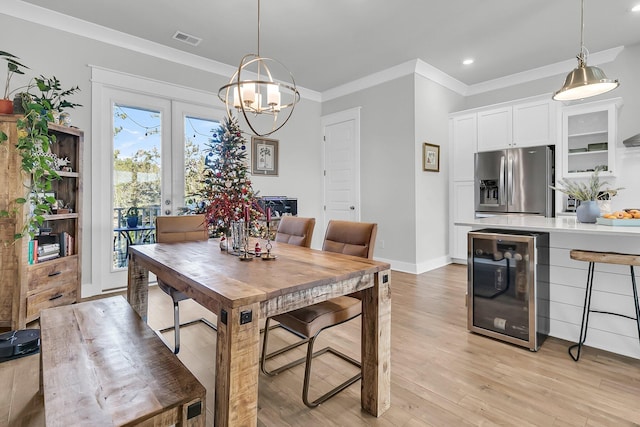 dining space with a notable chandelier, light hardwood / wood-style floors, ornamental molding, and beverage cooler