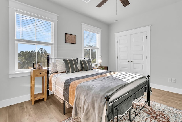 bedroom featuring multiple windows, ceiling fan, a closet, and light wood-type flooring