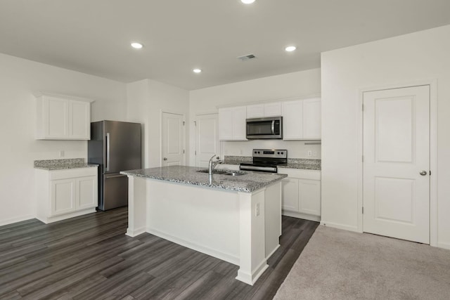 kitchen with a center island with sink, visible vents, appliances with stainless steel finishes, light stone countertops, and a sink