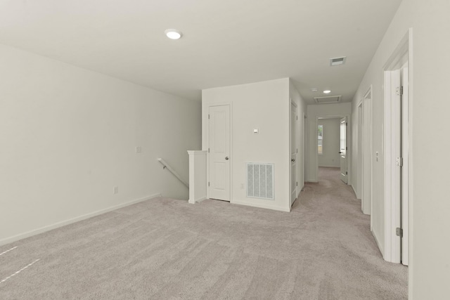 spare room with attic access, light colored carpet, visible vents, and baseboards