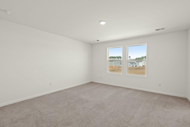 carpeted spare room with visible vents and baseboards