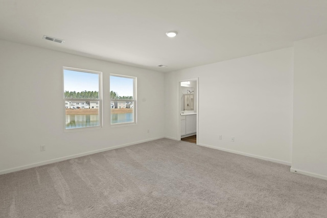 spare room with carpet, visible vents, and baseboards