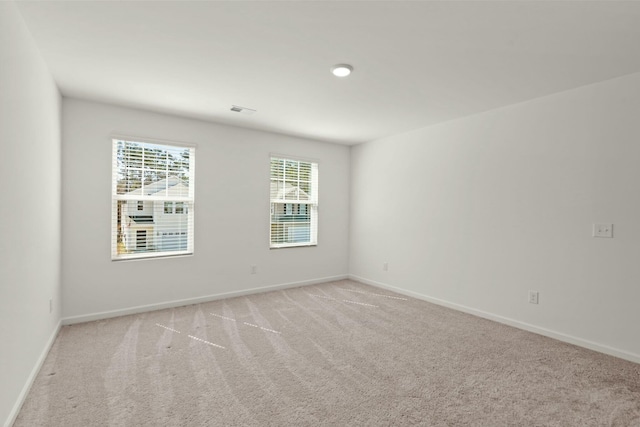 empty room with light carpet, visible vents, and baseboards