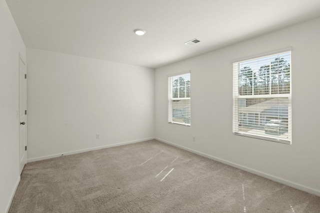 empty room featuring light carpet, visible vents, and baseboards