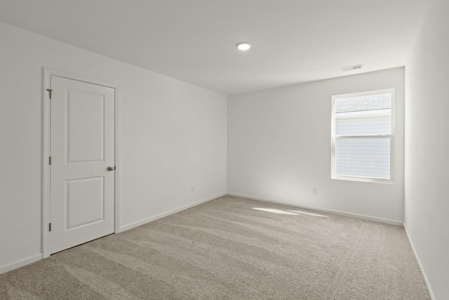 carpeted spare room with visible vents and baseboards