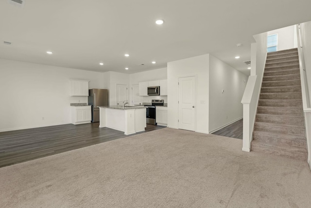 unfurnished living room with stairway, dark carpet, visible vents, and recessed lighting