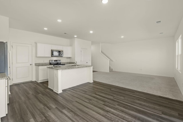 kitchen with a center island with sink, white cabinets, appliances with stainless steel finishes, a sink, and recessed lighting