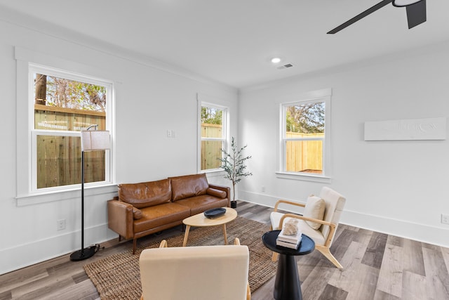 living room featuring ceiling fan, wood finished floors, visible vents, and baseboards