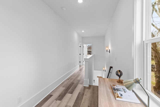 hallway featuring a healthy amount of sunlight, baseboards, wood finished floors, and an upstairs landing