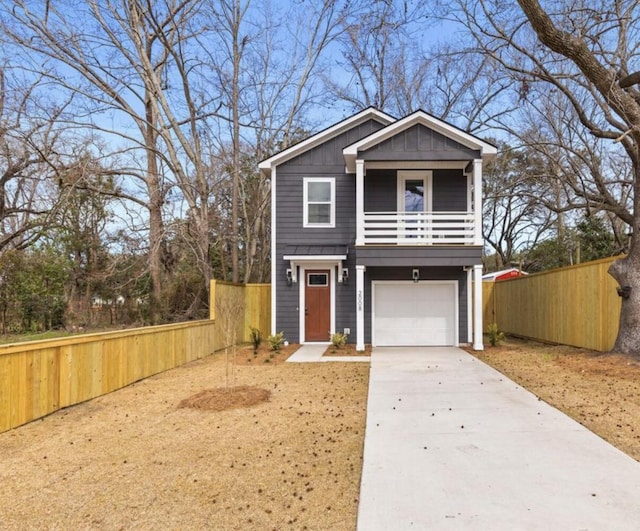 traditional-style home with an attached garage, a balcony, fence, driveway, and board and batten siding