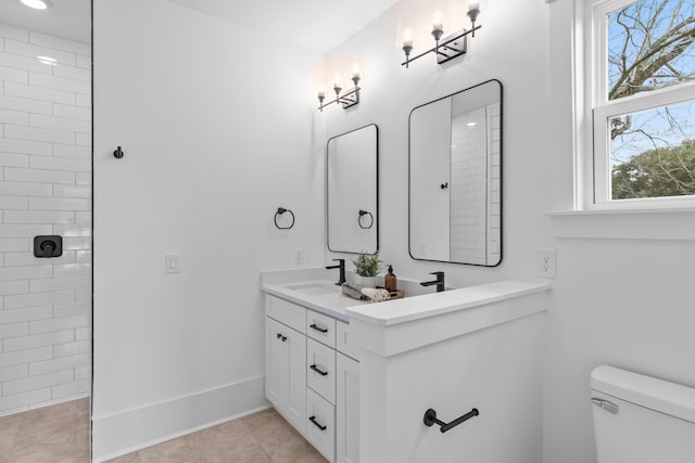 bathroom with double vanity, tiled shower, toilet, tile patterned floors, and a sink