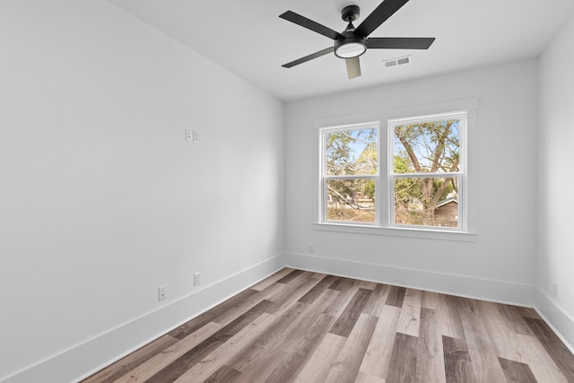 empty room featuring ceiling fan, wood finished floors, visible vents, and baseboards