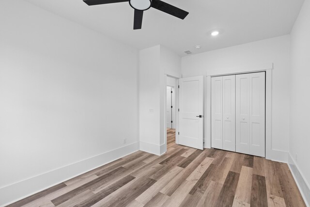 unfurnished bedroom featuring a ceiling fan, a closet, baseboards, and wood finished floors