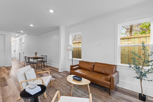 living room with recessed lighting, crown molding, and wood finished floors