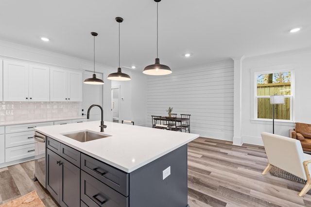 kitchen with a sink, light wood-style floors, white cabinets, light countertops, and tasteful backsplash