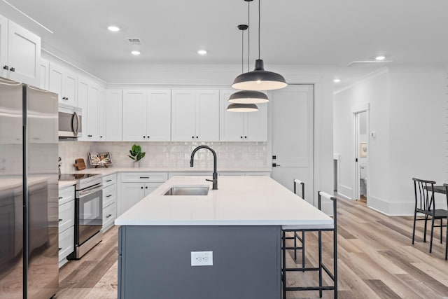 kitchen with light countertops, visible vents, appliances with stainless steel finishes, a sink, and a kitchen breakfast bar