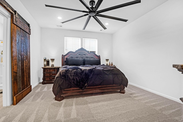 carpeted bedroom with ceiling fan and a barn door