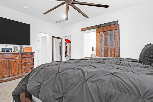 bedroom featuring carpet, ceiling fan, a barn door, a spacious closet, and a closet