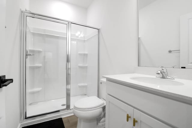 bathroom featuring vanity, wood-type flooring, an enclosed shower, and toilet