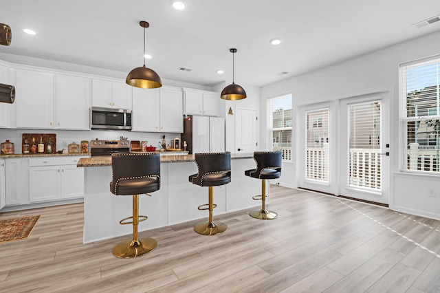 kitchen featuring dark stone countertops, white cabinets, a kitchen island, and stainless steel appliances