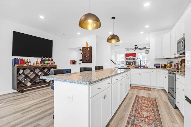 kitchen featuring light stone countertops, white cabinetry, pendant lighting, and appliances with stainless steel finishes