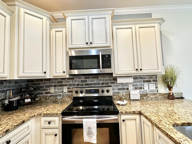 kitchen with ornamental molding, stainless steel appliances, and cream cabinetry