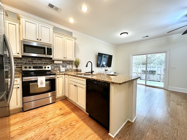 kitchen featuring appliances with stainless steel finishes, a peninsula, crown molding, cream cabinetry, and a sink