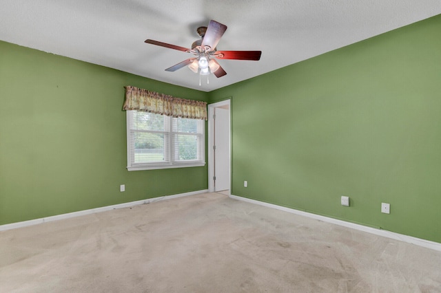 empty room featuring a textured ceiling, light colored carpet, and ceiling fan