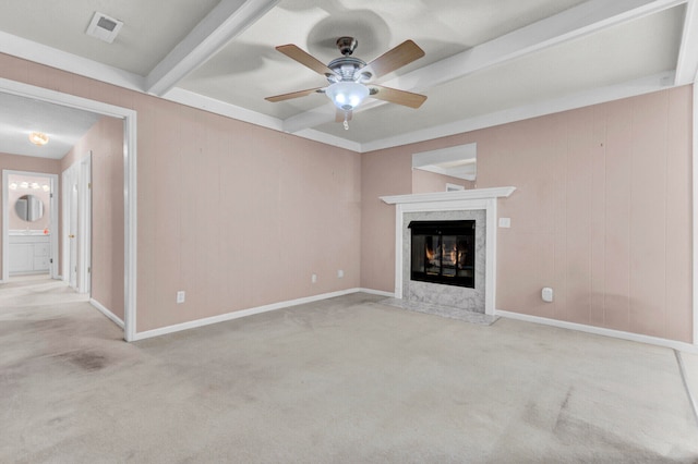 unfurnished living room with a premium fireplace, light colored carpet, beamed ceiling, and ceiling fan