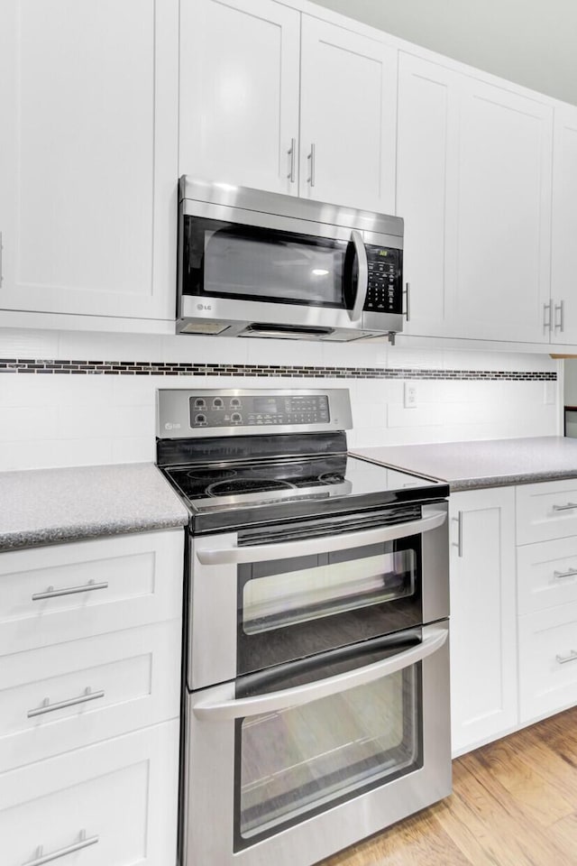 5406 Dwight Dr, North Charleston, SC 29420 - kitchen with stainless steel appliances, backsplash, and white cabinetry