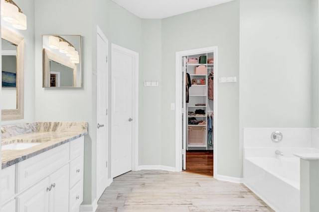 5406 Dwight Dr, North Charleston, SC 29420 - bathroom with wood finished floors, vanity, a garden tub, and a walk in closet