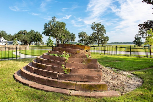 exterior space featuring a rural view, a lawn, and fence