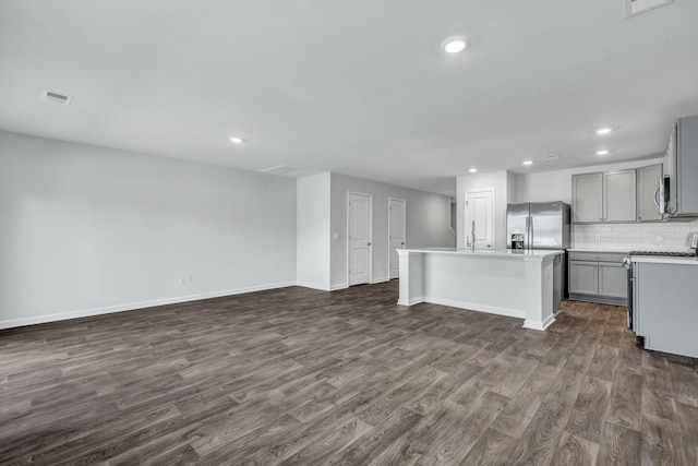 kitchen featuring a center island with sink, gray cabinetry, dark wood-type flooring, stainless steel refrigerator with ice dispenser, and backsplash