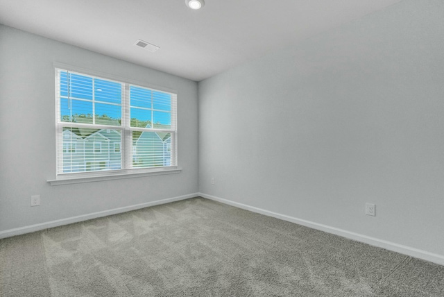 carpeted spare room with visible vents and baseboards