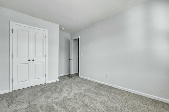 unfurnished bedroom with a closet, baseboards, and carpet