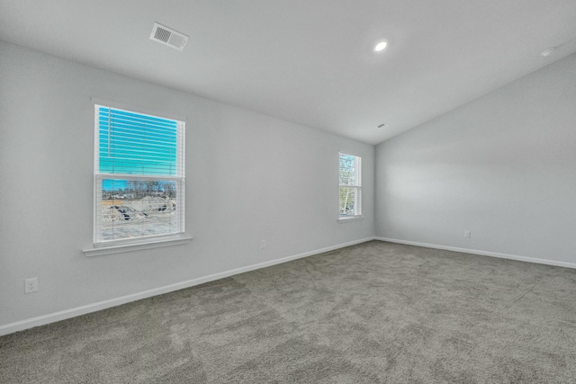 carpeted spare room with visible vents, baseboards, and lofted ceiling