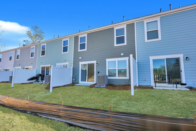 back of property with central AC unit, a yard, and fence