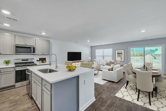 kitchen featuring visible vents, gray cabinets, a sink, dark wood finished floors, and appliances with stainless steel finishes