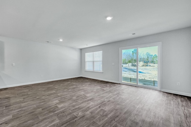 unfurnished room with visible vents, baseboards, and dark wood-style flooring