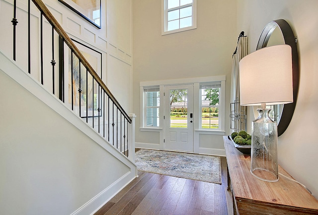 foyer featuring stairs, a high ceiling, wood-type flooring, and baseboards