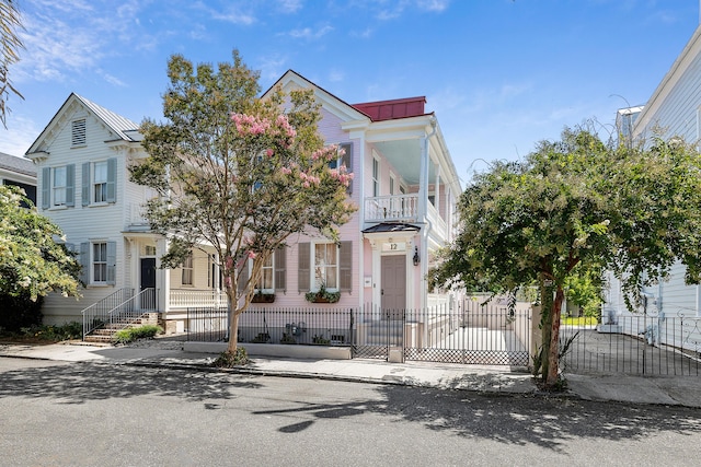 view of front of house with metal roof, a fenced front yard, and a balcony