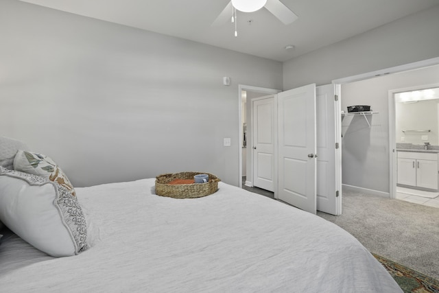 bedroom featuring ceiling fan, light colored carpet, a closet, and a walk in closet