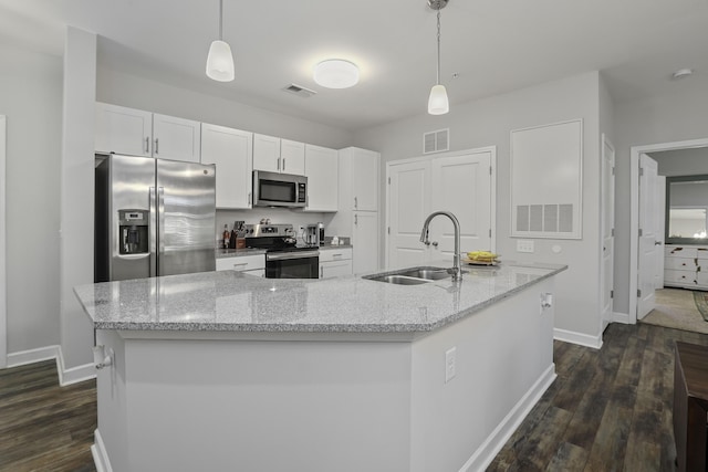 kitchen featuring decorative light fixtures, white cabinetry, appliances with stainless steel finishes, and a kitchen island with sink