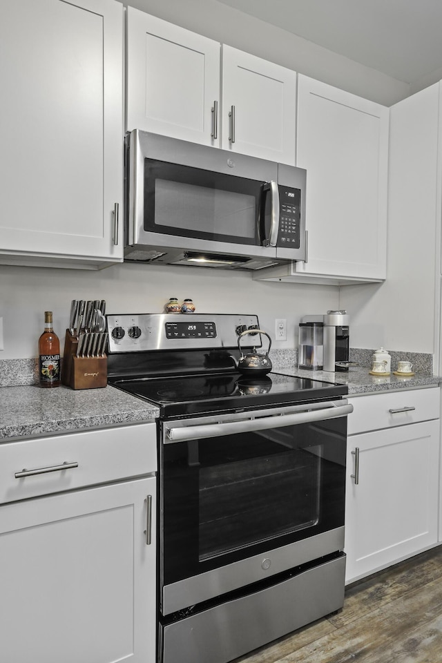 kitchen with white cabinets, appliances with stainless steel finishes, and dark hardwood / wood-style flooring