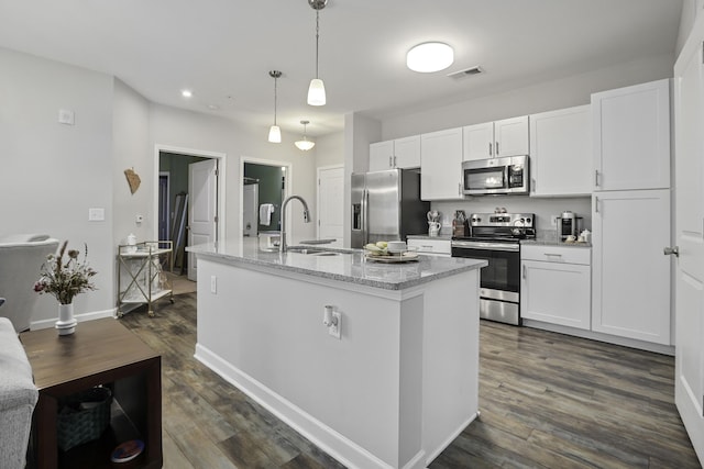 kitchen with pendant lighting, white cabinets, appliances with stainless steel finishes, sink, and a kitchen island with sink