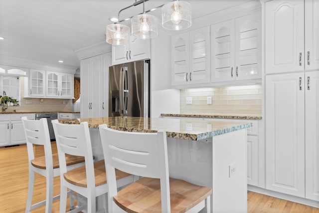 1551 Hutton Pl, Charleston, SC 29407 - kitchen with appliances with stainless steel finishes, a kitchen breakfast bar, glass insert cabinets, backsplash, and light wood-type flooring